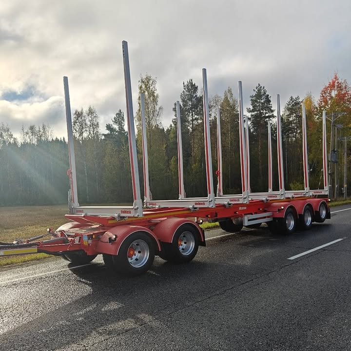 Uusi punainen puutavaraperävaunu tiellä